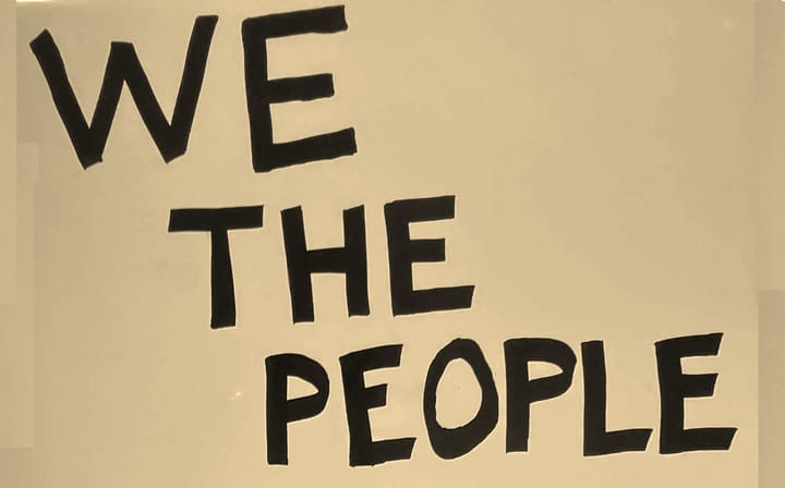 hand lettered "We The People" sign